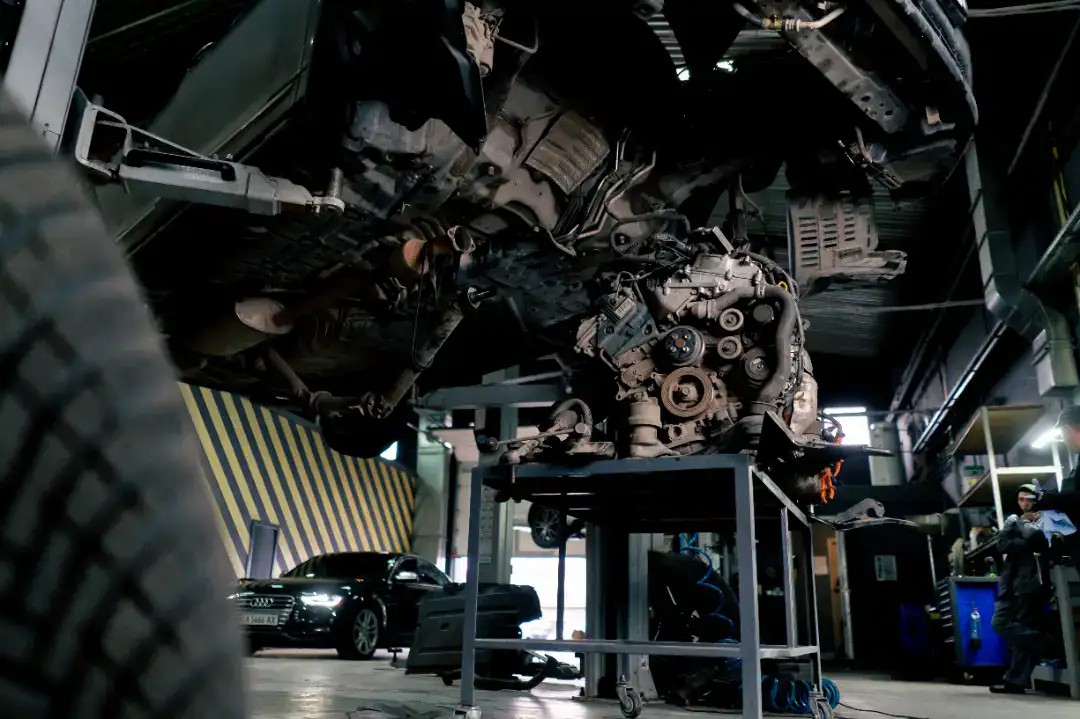 Automekaniker arbejder på bilmotor i værksted.