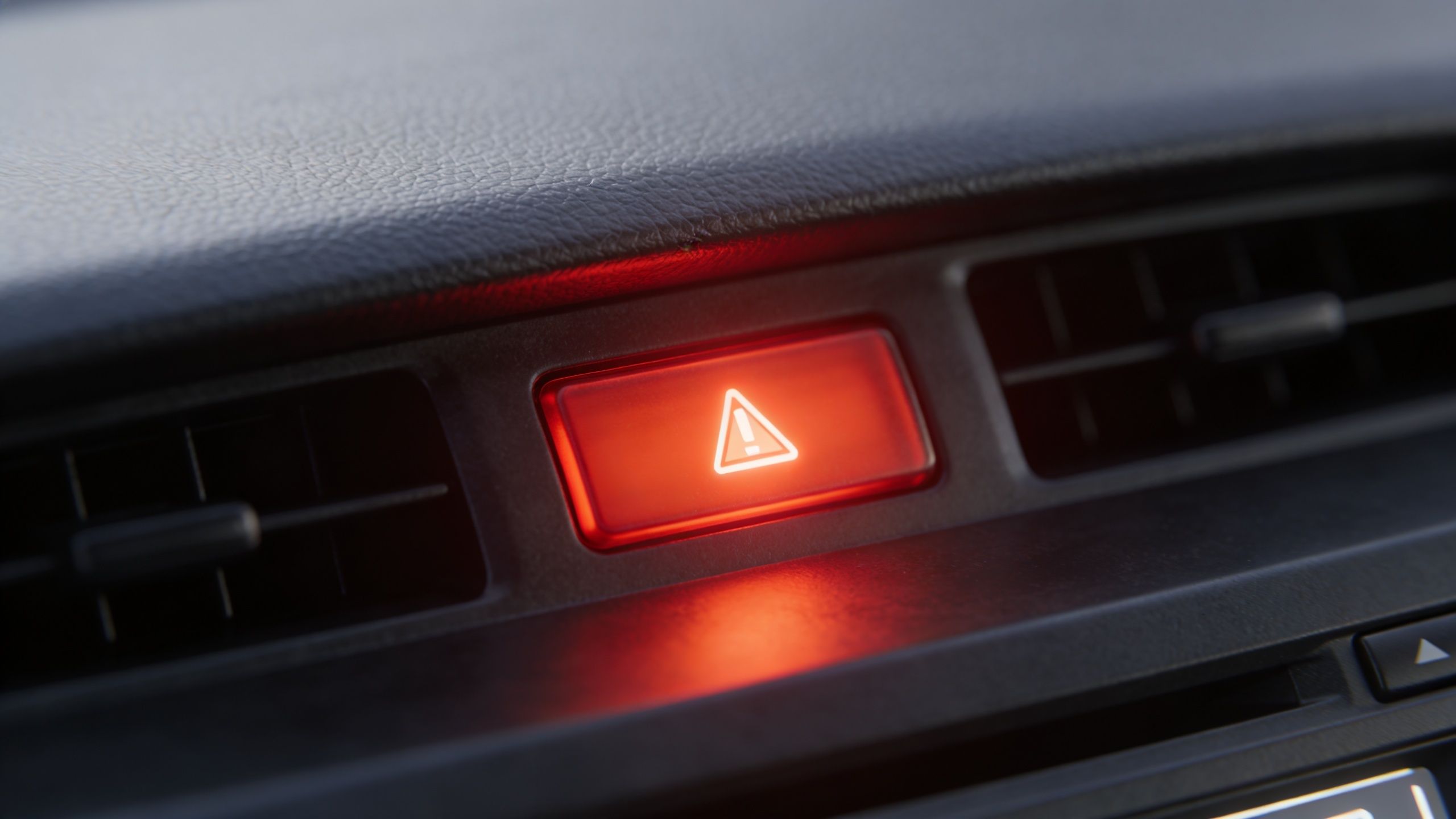 Et tændt advarselsblink-symbol på instrumentbrættet i en bil, der indikerer brug af havariblinket.