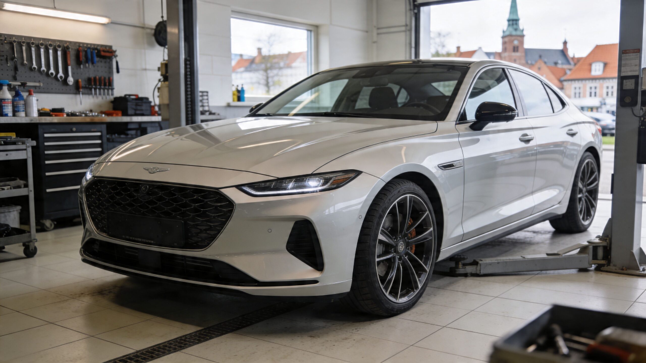 En sølvfarvet Genesis luksusbil holder løftet på et professionelt autoværksted til inspektion eller serviceeftersyn.